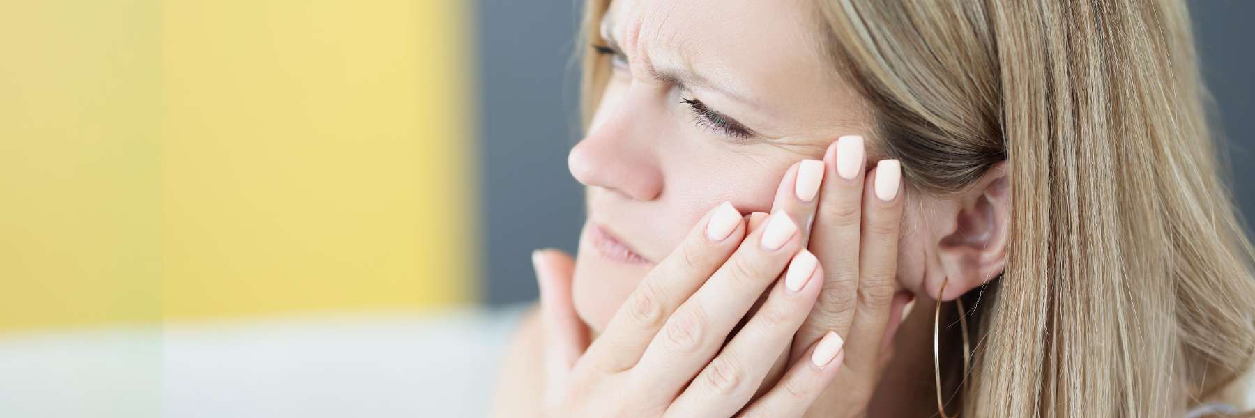 blonde woman holding jaw | sydney emergnecy dentistry